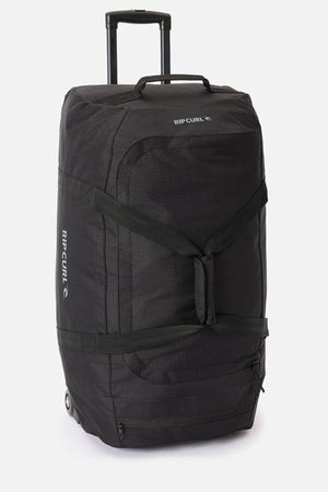 The Rip Curl Jupiter 80L travel bag, large and black with a telescopic handle, side straps, and durable inline skate wheels, stands upright against a plain white background.