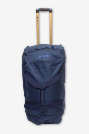 A Rip Curl Jupiter 80L Mixed Travel Bag in navy blue with gold-colored handles is displayed. This travel bag boasts lightweight construction, multiple straps, and several compartments. It stands upright against a white background.