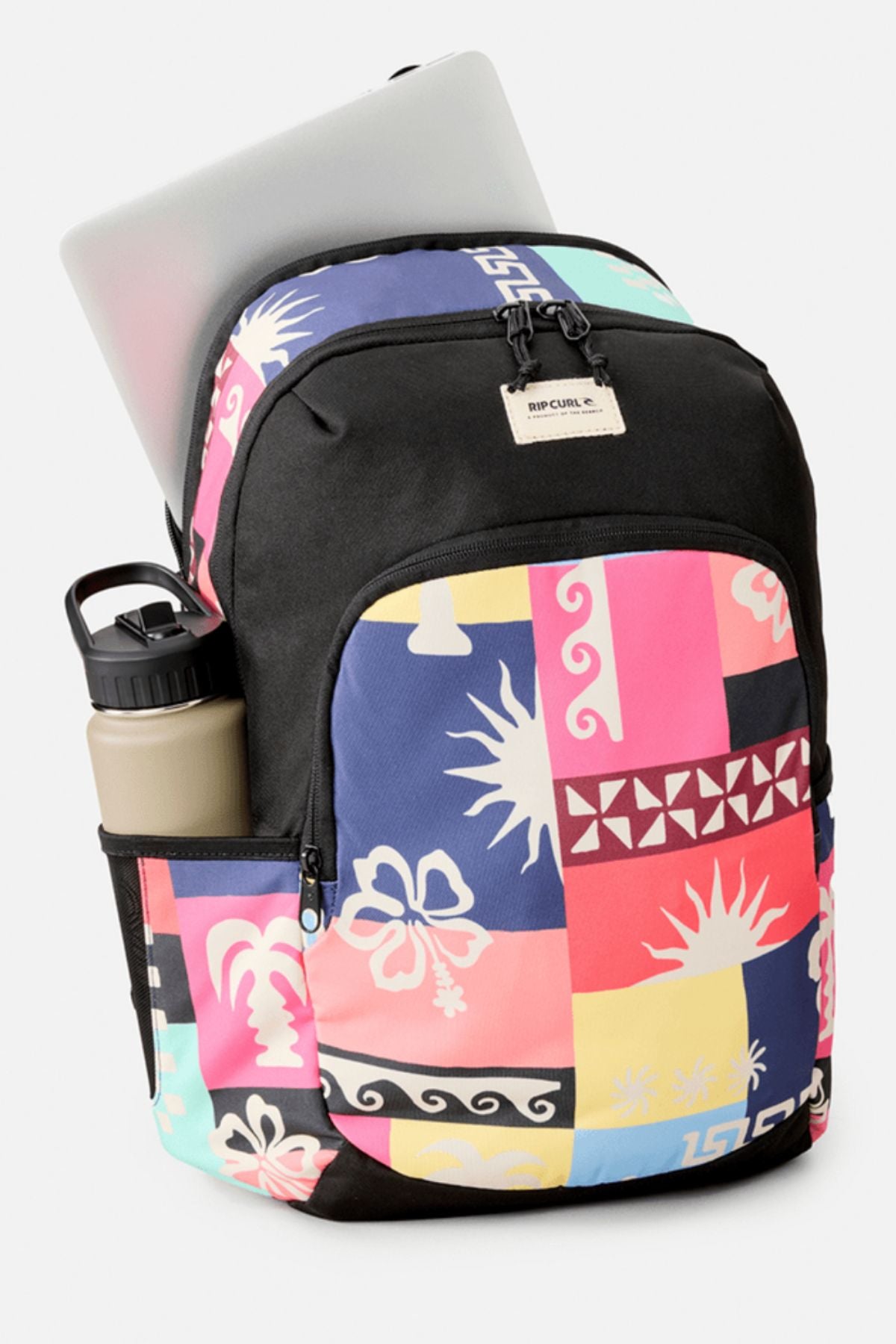 The Rip Curl Ozone 2.0 30L Backpack displays abstract pink, blue, yellow, and black patterns, with a front zip pocket, a water bottle in the side pocket, and a laptop partly inside the main compartment.