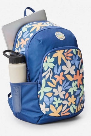 The Rip Curl Ozone 2.0 30L Backpack is blue with vibrant floral front pocket designs, a side mesh pocket holding a white water bottle, and a laptop compartment with the computer partially visible from the top.