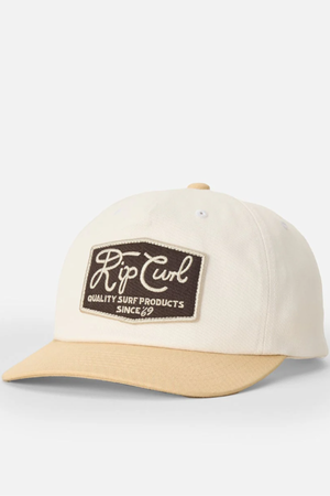 The Rip Curl Pacific Rinse SB Cap is a cream cap with a tan brim and brown front patch reading "Rip Curl Quality Surf Products Since 69" in white—an unstructured, stylish choice for the beach.