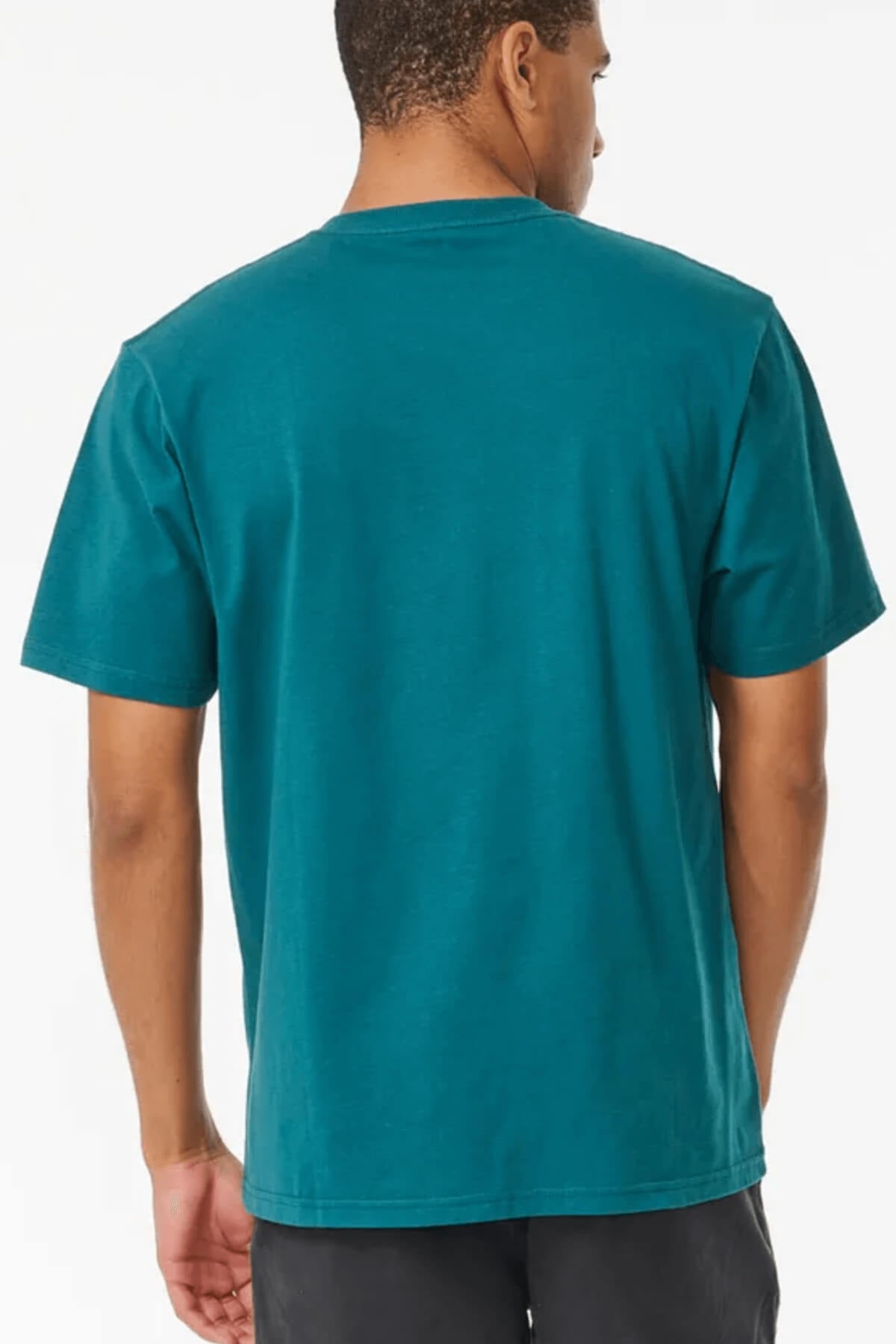 A person in a Rip Curl Pill Icon Tee, crafted from 100% cotton with short sleeves, stands against a plain backdrop wearing dark pants. Their head is turned slightly to one side.