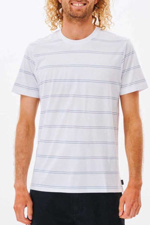 With their curly hair adding to the relaxed look, the person embodies pure comfort in a Rip Curl Plain Stripe Tee made of 100% cotton, paired seamlessly with black pants against a plain white backdrop.