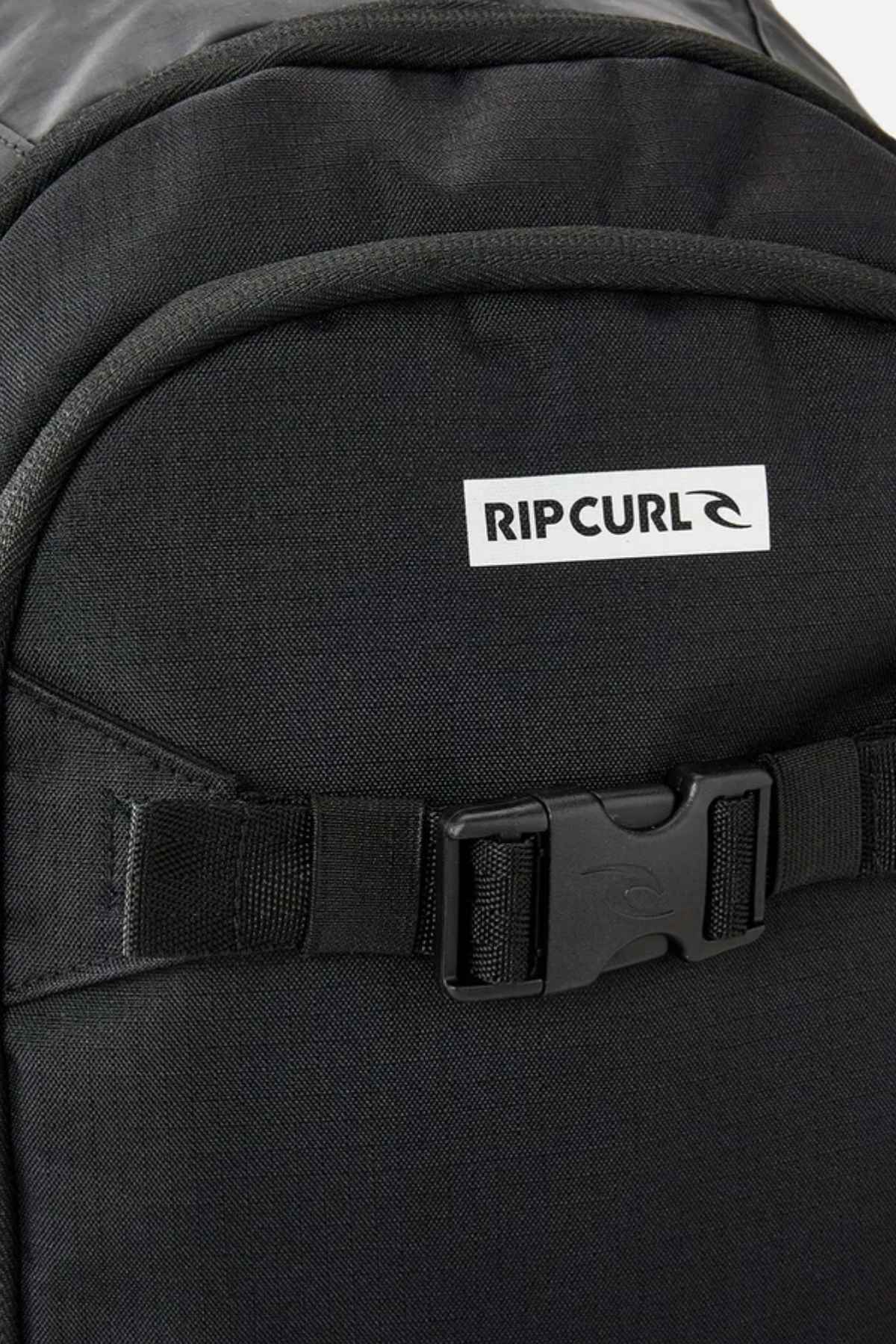 Close-up of the Rip Curl Posse 33L Icons Backpack, showcasing its sleek black design made from recycled polyester. The image emphasizes the top section with prominent buckle strap detailing and a dedicated laptop compartment for enhanced convenience.