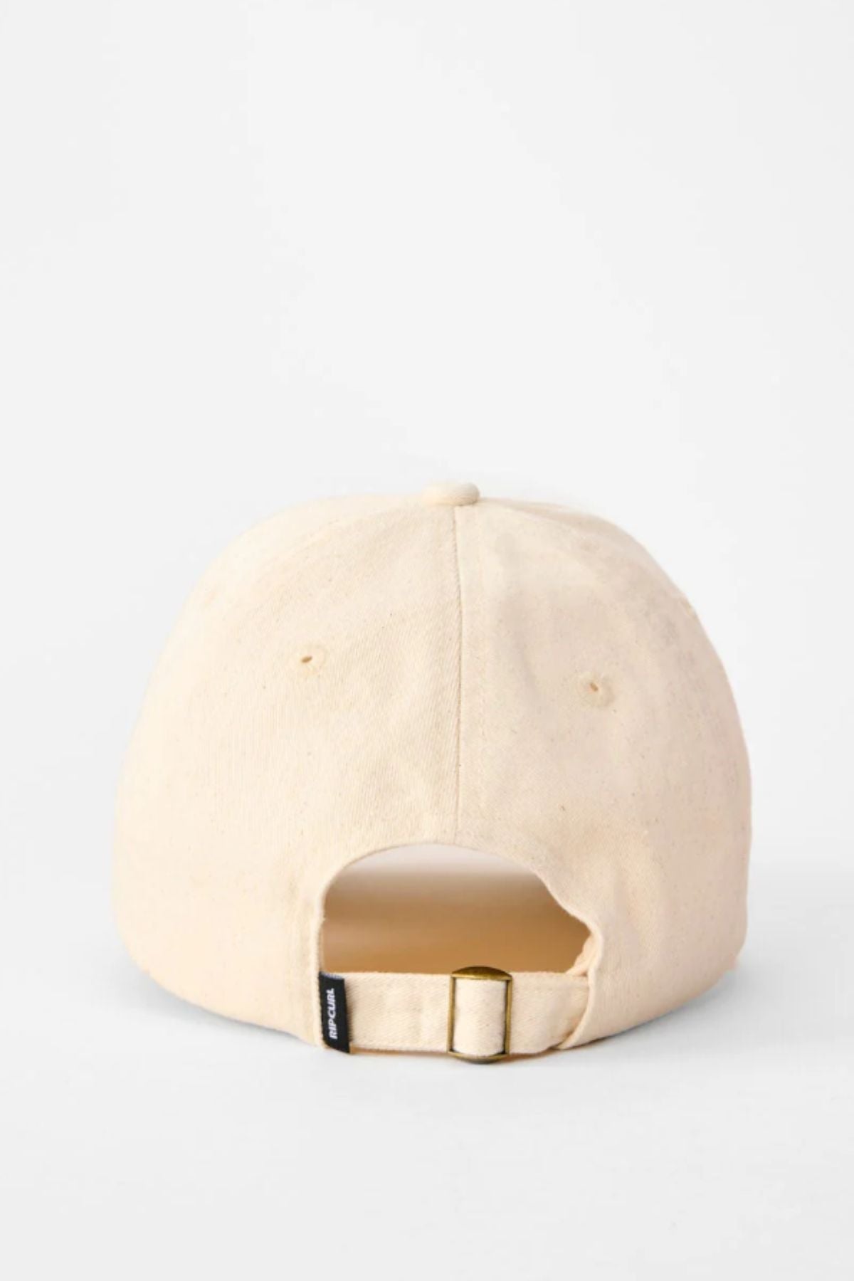 The Rip Curl Premium Surf Cap in beige cotton twill is shown from the back, displaying a fabric strap with metal buckle for size adjustment and a small black tag. The background is plain white.