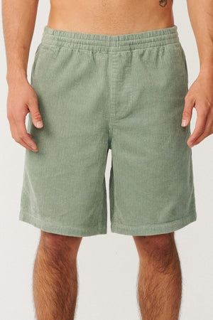 A person wearing the Rip Curl Premium Surf Cord 19" Volley shorts in light green, featuring an elastic waistband and classic surf-inspired styling, is shown from the waist to above the knees against a plain background.