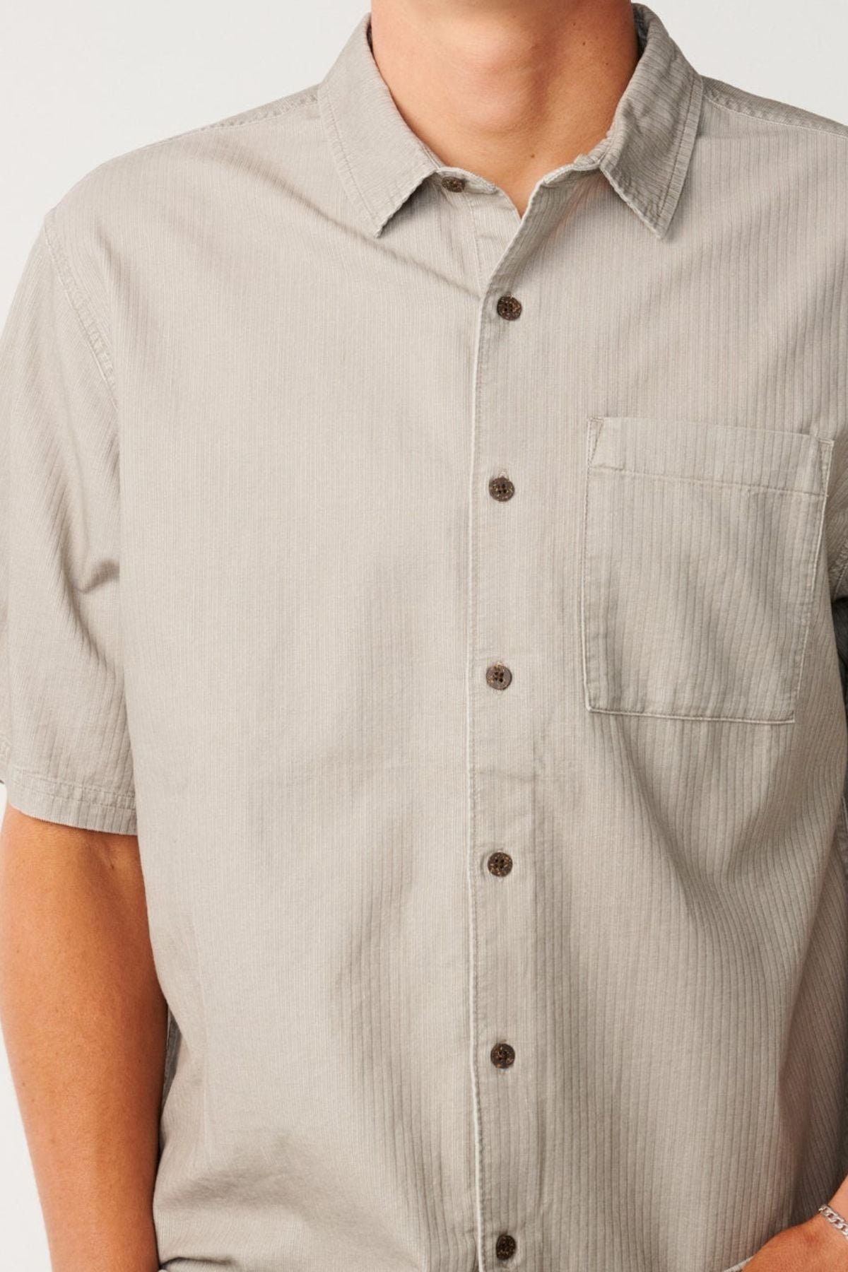 Wearing the Rip Curl Premium Surf Cord Short Sleeve Shirt in light gray, featuring a chest pocket, this person showcases a relaxed vintage aesthetic ideal for casual occasions.