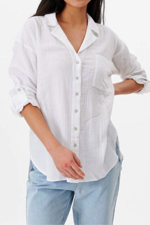 A person wears the Rip Curl Premium Surf Long Sleeve Button Up Shirt with sleeves rolled up and light blue jeans, standing against a plain white background.