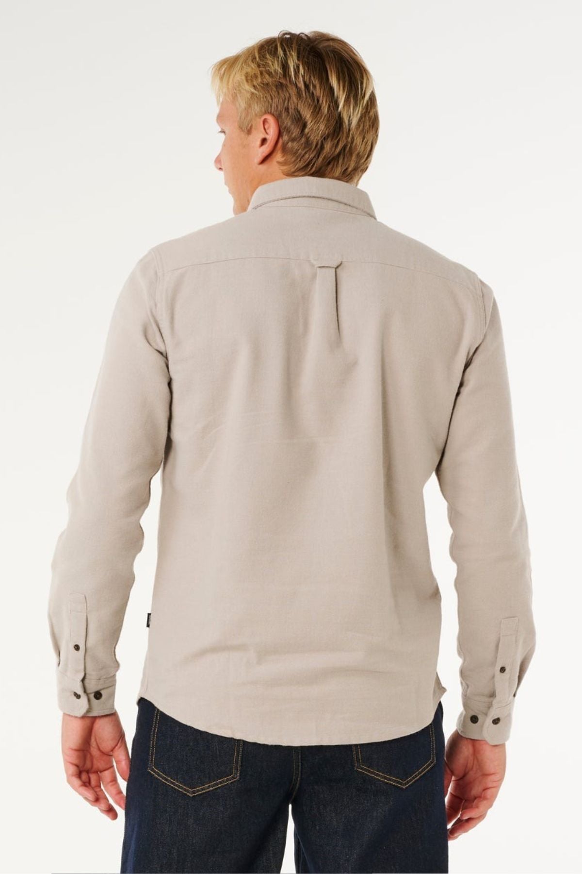 A man with short blonde hair is shown from the back, wearing a Rip Curl Premium Surf Flannel and dark blue jeans, standing against a plain white background.