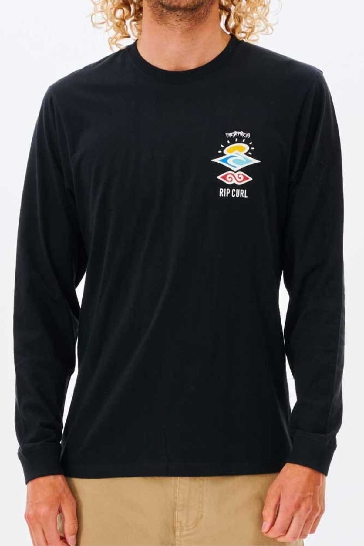 A person in a black Rip Curl Search Icon Long Sleeve Tee, crafted from soft organic cotton jersey with a small colorful graphic and Rip Curl logo on the left chest, paired with light brown pants.