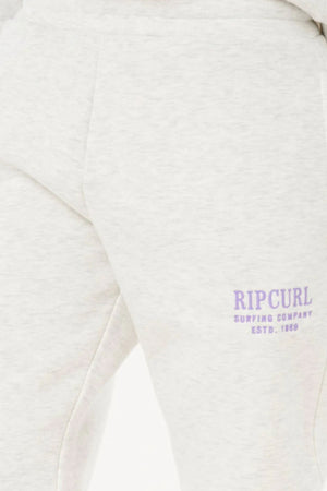 Close-up of a person in Rip Curl Surf Staple Trackpant, light gray with "RIP CURL SURFING COMPANY ESTD. 1969" in light purple by the pocket—ideal for casual wear.