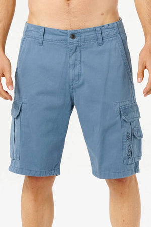 Someone is wearing the Rip Curl Classic Surf Trail Cargo Short in light blue cotton, featuring side pockets, a button closure, belt loops, and visible stitching. The relaxed fit shorts are shown against a plain white background.