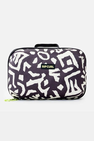 The Rip Curl Ultimate Beauty Case is a rectangular black fabric bag adorned with white geometric patterns and a small "Rip Curl" logo in the center. It features a black handle on top and a small green zipper pull on the bottom left side, making it an ideal travel companion for your beauty essentials. The background is plain white.