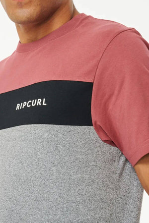 A person is wearing the Rip Curl Undertow Panel Tee, a comfortable short-sleeve shirt with a maroon top, black stripe with "RIPCURL" text, and gray lower panel. Only part of their face and upper body are shown.