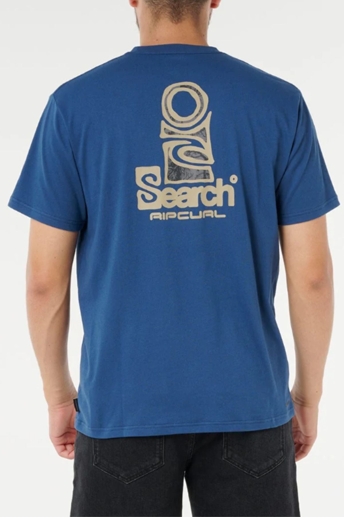 A person seen from the back wears a blue Rip Curl Vaporcool Search Stack Tee featuring a large abstract logo and "Search Rip Curl" in light beige on the upper back; this moisture-wicking t-shirt ensures cool comfort.