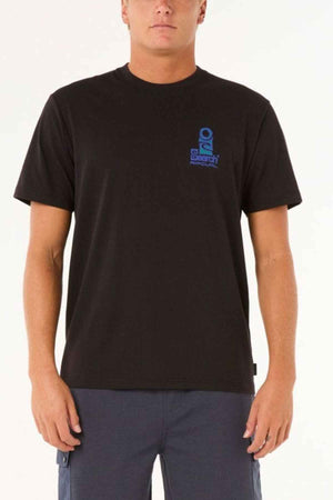 A person wearing the Rip Curl Vaporcool Search Stack Tee, featuring a small blue logo on the upper left corner, stands against a plain background. The Vaporcool fabric ensures comfort, while their dark blue pants complete the look, making it perfect for staying cool and stylish all day.