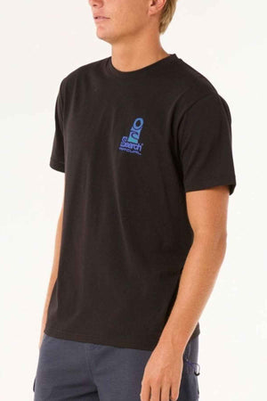 A person wearing the Rip Curl Vaporcool Search Stack Tee in black, showcasing "Search" and a blue logo on the chest with moisture-wicking fabric for added comfort, stands against a neutral background. They complement it with stylish dark blue pants.