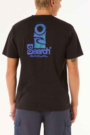 A person is wearing the Rip Curl Vaporcool Search Stack Tee, a black T-shirt featuring the word "Search" and a blue abstract logo on the back, made from moisture-wicking fabric for enhanced comfort. They complement it with blue pants and have short hair against a plain white background.