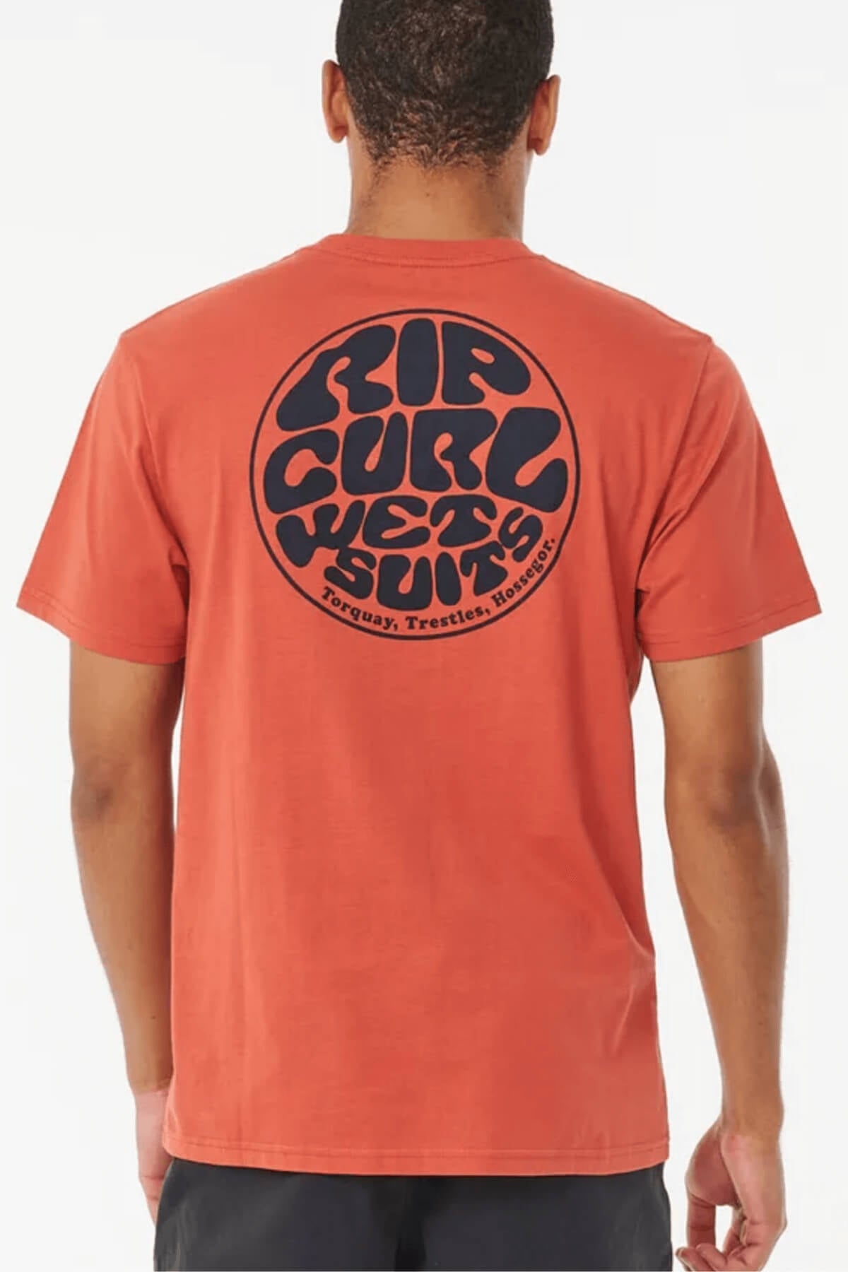 Wearing the Rip Curl Wetsuit Icon Tee—a reddish-orange breathable cotton shirt with a bold black "Rip Curl Wetsuits" circle logo and "Torquay, Trestles, Hossegor" on the back—is ideal for any outdoor activity.