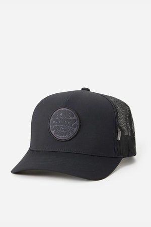 The Rip Curl Wetsuit Icon Trucker is a black cap with a mesh back and circular embroidered front logo patch, made from recycled polyester for outdoor activities, shown on a plain white background.