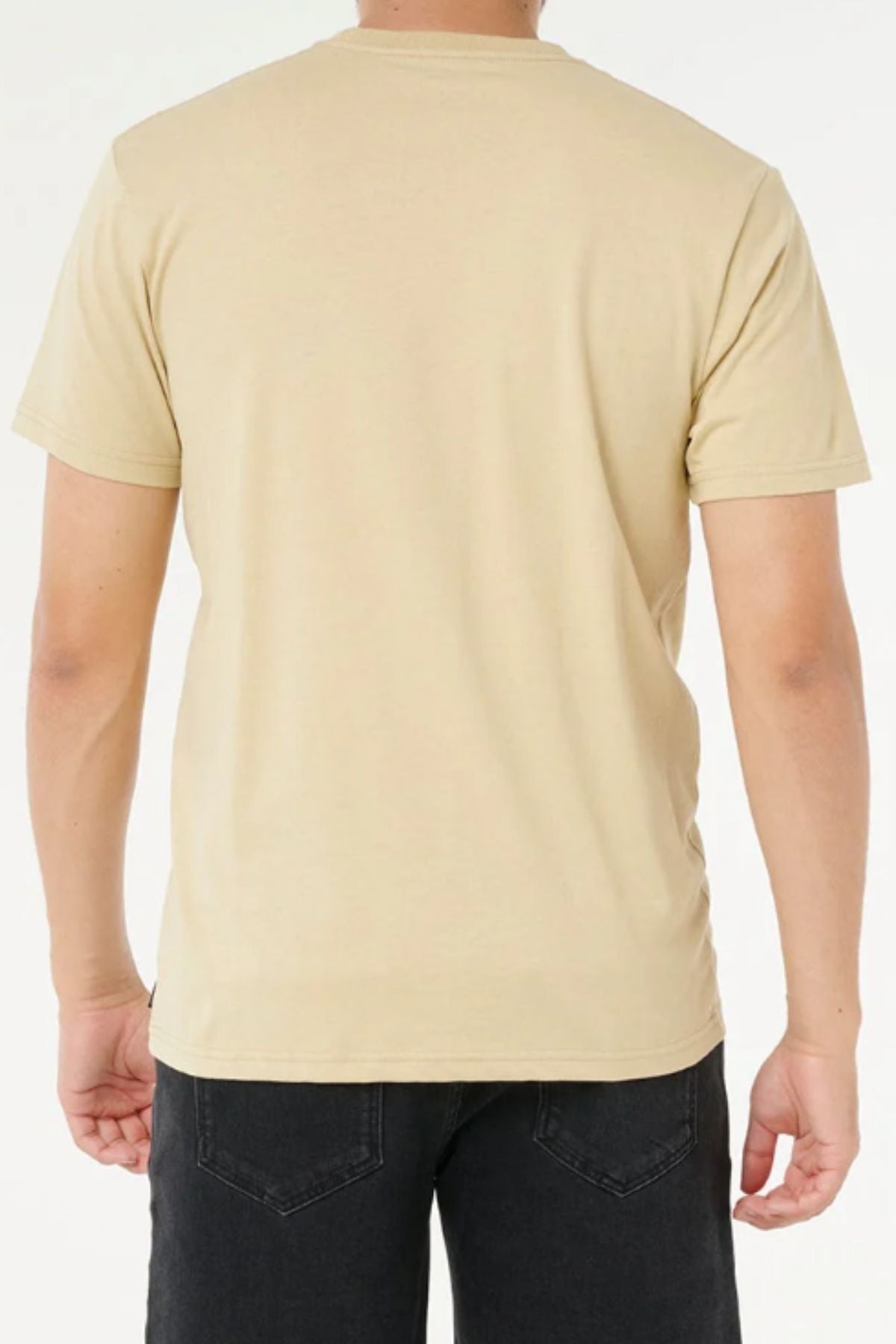 A person is seen from the back against a white background, wearing the Rip Curl Wettie Icon Tee in plain beige 100% cotton paired with black jeans.