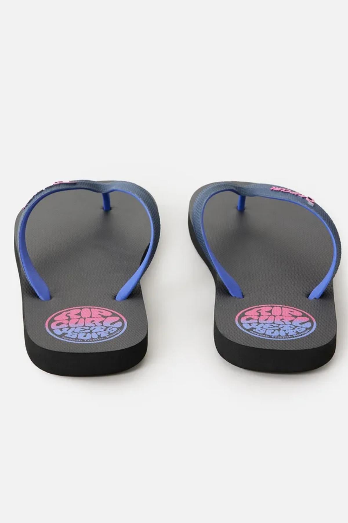 A pair of Rip Curl Wetty Fade Bloom Thongs in black with blue straps. The footbeds feature a colorful circular logo near the heel with the text "5050 SLIDE." The soles are slightly elevated at the heel, and the thongs are positioned with the toe area facing forward.