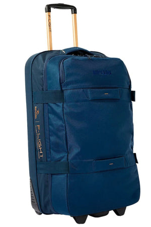 The Rip Curl F-Light Global 100L Sapphire Travel Bag is a blue rolling suitcase made from recycled polyester, featuring multiple compartments and a hard bottom. It includes two wheels and an extendable handle, with the Rip Curl logo prominently displayed on the front.