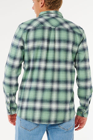 A person is shown from the back against a plain white background wearing blue jeans and a green, black, and white Rip Curl Count Flannel Shirt.