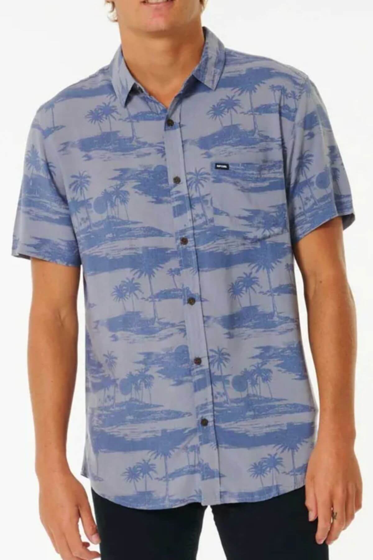 Wearing the Rip Curl Party Pack Short Sleeve Shirt with a tropical palm tree and island print, a person with a comfortable fit stands against a plain white background.