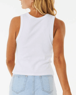 Rear view of a person with long blonde hair wearing a Rip Curl Classic Ribbed Tank in white made from Cotton Elastane, along with light blue jeans, against a plain background.