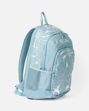 The Rip Curl Ozone 2.0 30L Backpack features a light blue design with bold white floral prints, mesh side pocket, padded shoulder straps, front zip pocket, laptop compartment, top front "RIP CURL" logo, and is crafted from recycled polyester.
