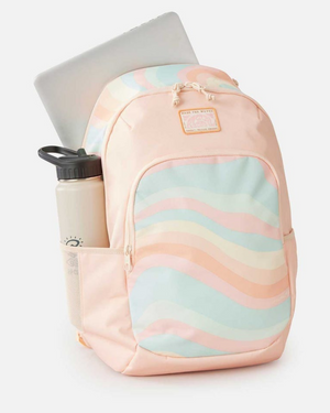 The Rip Curl Ozone 2.0 30L Backpack, made from 100% recycled polyester, boasts pastel wavy stripes in pink, blue, and orange. It includes a laptop section and a snug side pocket for a beige water bottle. A front patch reads "Here for This.