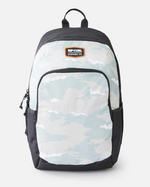 The Rip Curl Ozone 30L School Backpack showcases a light camo front and top, black sides and trim, a top handle, and two side pockets. Made from recycled polyester, it's photographed on a plain white background.