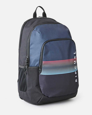 The Rip Curl Ozone 30L School Backpack features a black and blue recycled polyester design with a front pocket showcasing horizontal multicolored stripes. "RIP CURL" appears vertically on the front. Ideal for school, it includes a top handle and adjustable shoulder straps for comfort.
