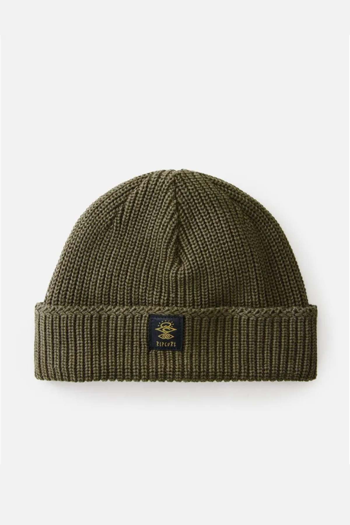 The Rip Curl Searchers Regular Beanie is an olive green knit with a folded brim and sherpa lining for warmth. A black patch with a design and illegible text decorates the front, adding a surf-inspired style, showcased on a white background.
