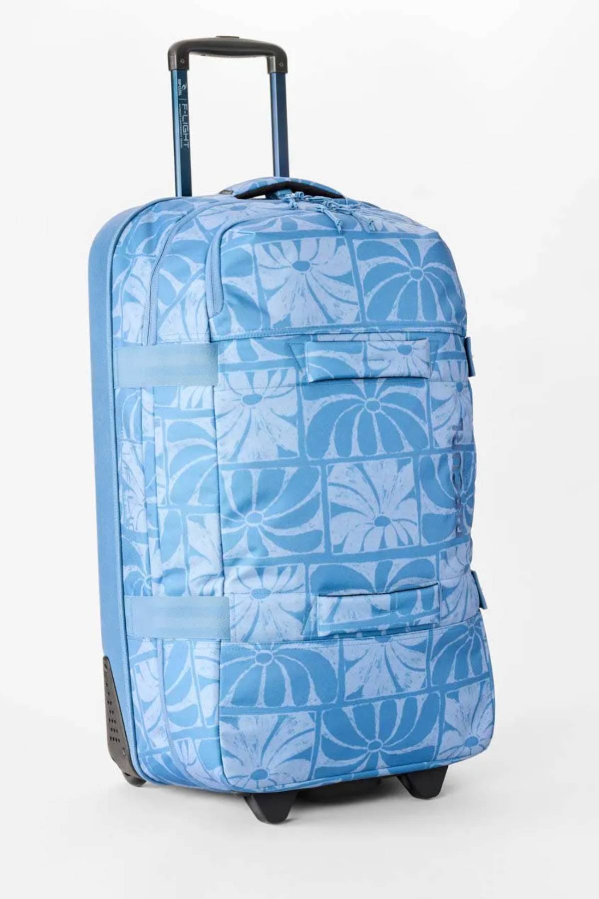 The Rip Curl F-Light Artist Of The Search Ty Williams 100L Global Travel Bag is a blue rolling suitcase with a retractable handle, light blue geometric and floral prints, wheels, exterior zip pockets, and a roomy 100L capacity.