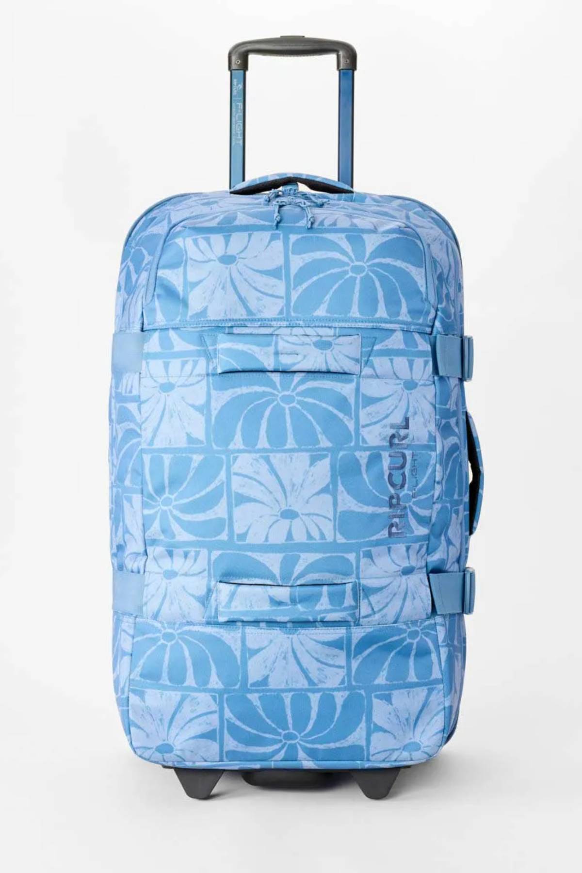 The Rip Curl F-Light Artist Of The Search Ty Williams 100L Global Travel Bag is a blue rolling travel bag with a telescopic handle, wheels, side straps, front zip pocket, and a lighter blue geometric floral pattern.
