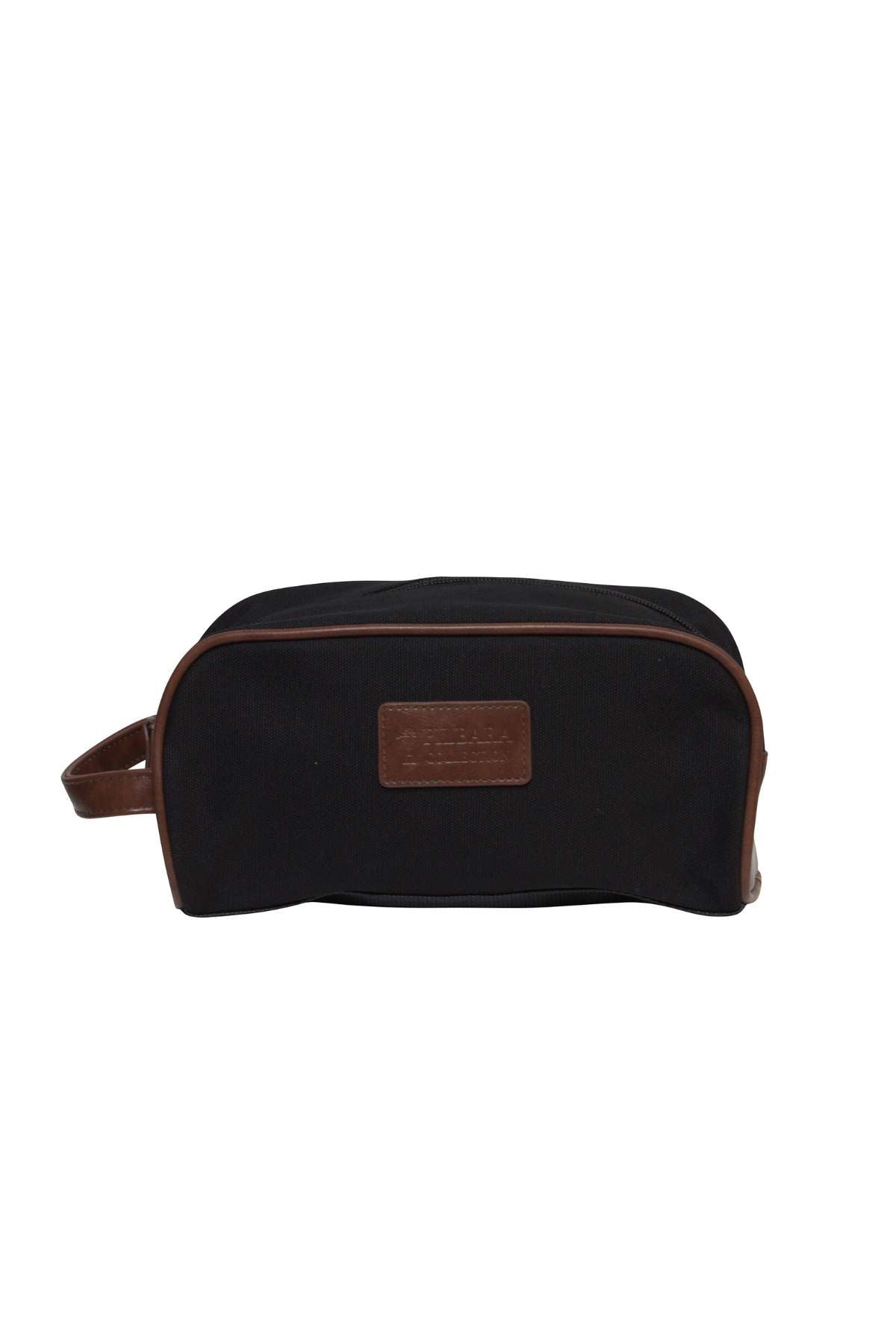 The Pilbara Toiletry Bag is a black fabric toiletry bag accented with brown leather trim and a small brown leather handle on one end. This premium canvas bag features a rectangular brown leather patch on the side with embossed text, making it an ideal choice for luxury travel.