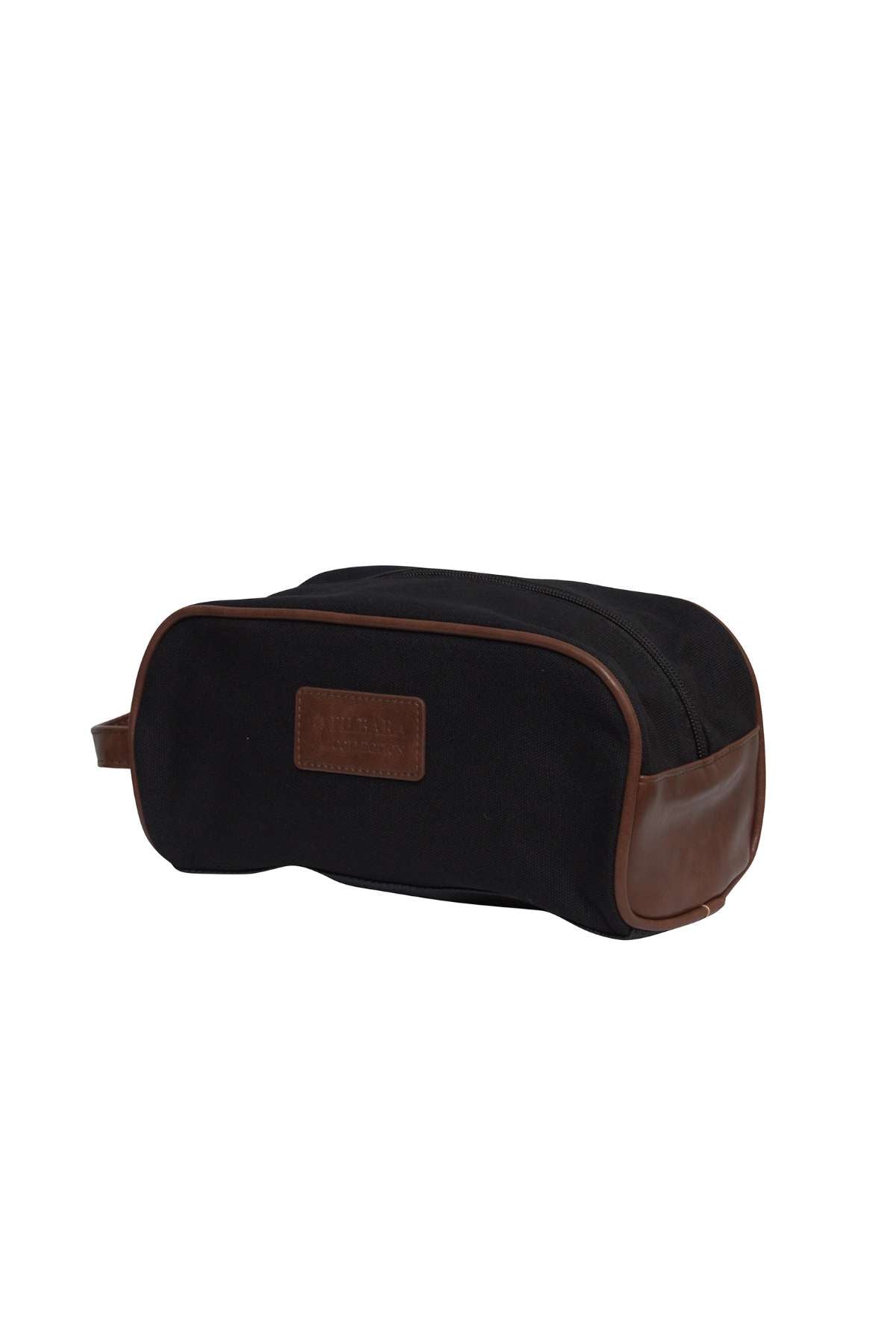 The Pilbara Toiletry Bag is a premium canvas toiletry bag featuring brown leather accents on the sides and edges, with a leather patch on one side. It includes a handle on one end and has a zipper running along the top, making it ideal for luxury travel.