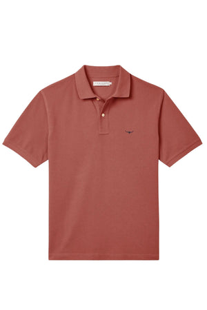 The RM Williams Rod Polo is a short-sleeved, brick red organic cotton shirt with a collar, two-button placket, and small dark Longhorn embroidery on the left chest, shown laid flat on a white background.