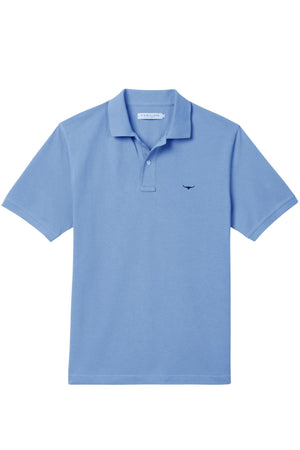 The RM Williams Rod Polo is a light blue classic polo shirt with a collar, button placket, and a small dark blue logo on the left chest. Made from soft organic cotton, it's shown on a plain white background.