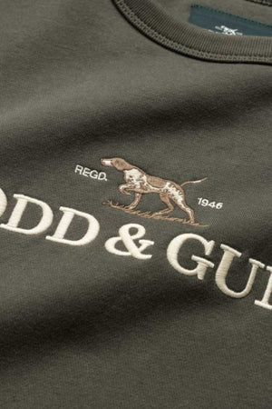 Close-up of a dark green Rodd & Gunn Gunn Logo Sweat, adorned with an embroidered brown and white dog in motion above "REGB. 1946," and partially visible "ODD & GU" in large white letters representing the brand's logo.