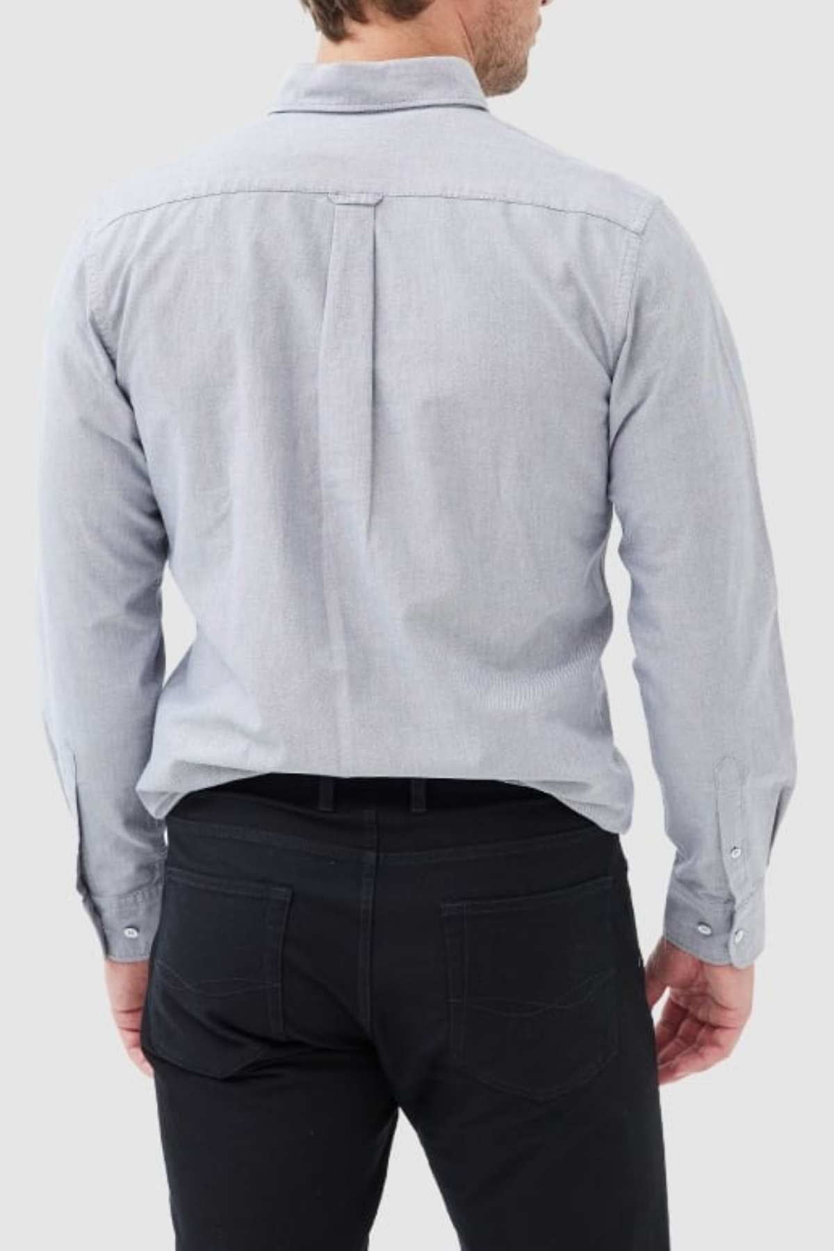 A man is seen from behind wearing the Rodd & Gunn Gunn Oxford Sports Fit Shirt in light gray, made from 100% cotton, paired with black pants. His hands hang by his sides against a plain, neutral background.