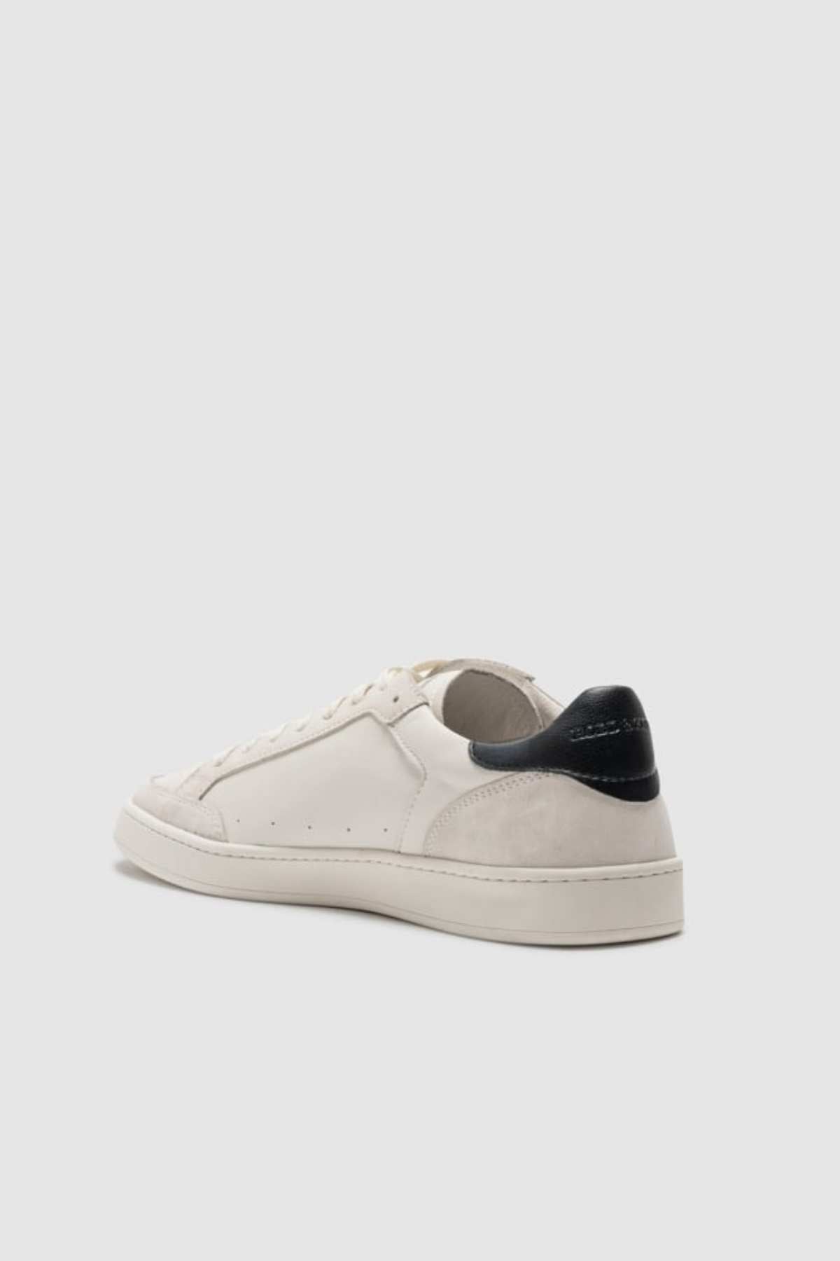 The Rodd & Gunn Sussex Street Sneaker is shown from a rear side angle, featuring a white design with a black heel tab and leather-lined interior, set against a plain light gray background.