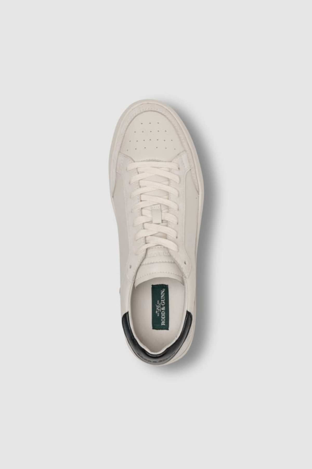 Top view of the Rodd & Gunn Sussex Street Sneaker: single white leather-lined shoe with white laces, perforated toe area, dark green heel tab, logo on insole, and a durable rubber outsole.