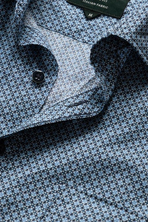A close-up of the Rodd & Gunn Chartwell Sports Fit Shirt in blue patterned fabric with small geometric designs, partially unbuttoned to reveal a label reading "ITALIAN FABRIC" and the size "M.