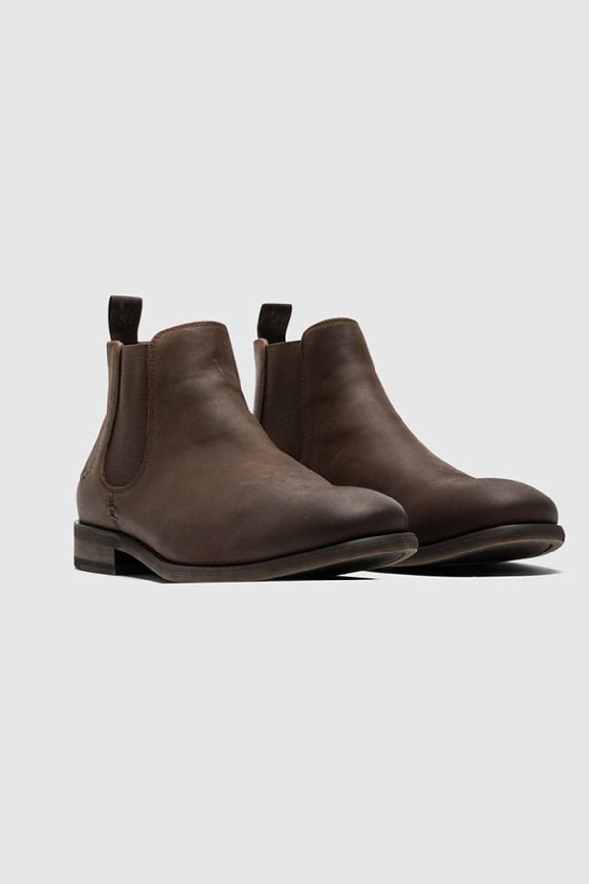 The Rodd & Gunn Ealing Chelsea Boot, crafted from brown oiled leather with elastic side panels, pull tabs, and a flexible rubber outsole, is displayed against a light gray background.