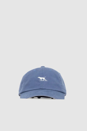 The Rodd & Gunn Gunn Cap is a blue cotton twill cap featuring a small white embroidered pointer dog logo on the front, shown against a plain light grey background.