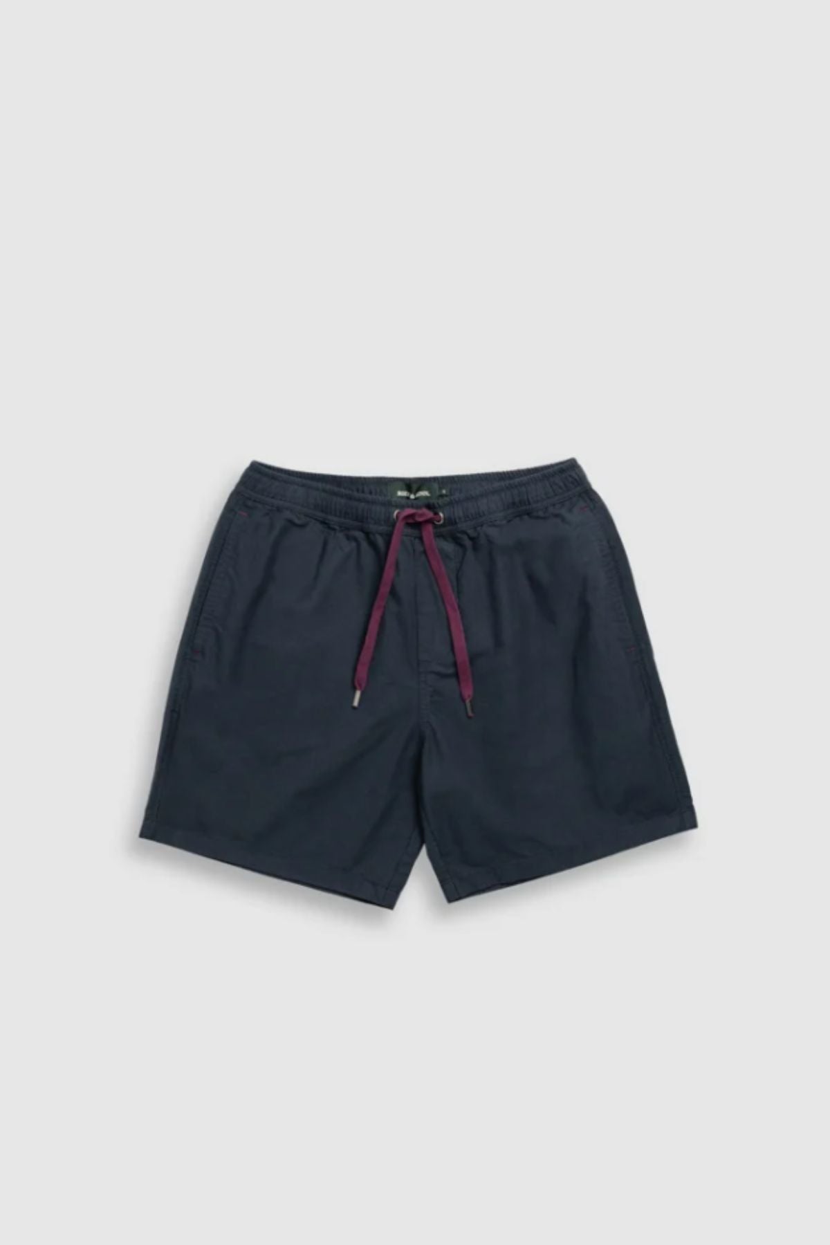 The Rodd & Gunn Resort Short is a navy blue cotton casual short featuring an elastic waistband, maroon drawstring, side pockets, and a relaxed fit for comfort. Shown flat on a light gray background.