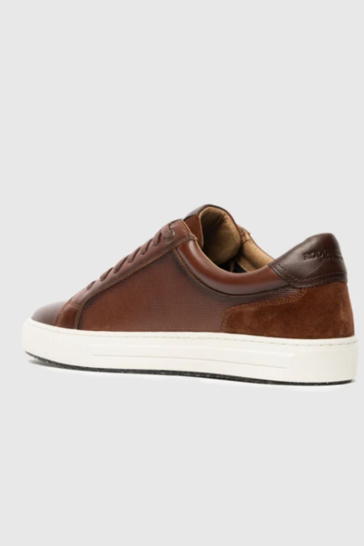 The Rodd & Gunn Transit Sneaker, a brown leather shoe with suede accents, white rubber sole, and brown laces, is displayed from the rear side against a plain light gray background.